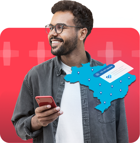 Imagem de um rapaz, sorrindo e de frente, mexendo no aplicativo Vale Saúde pelo celular